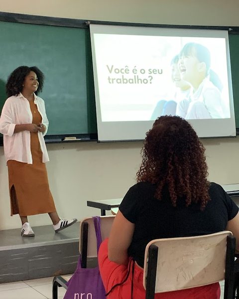 Thaís Marcelino durante uma palestra, diante de um slide com a pergunta “Você é o seu trabalho?”.
